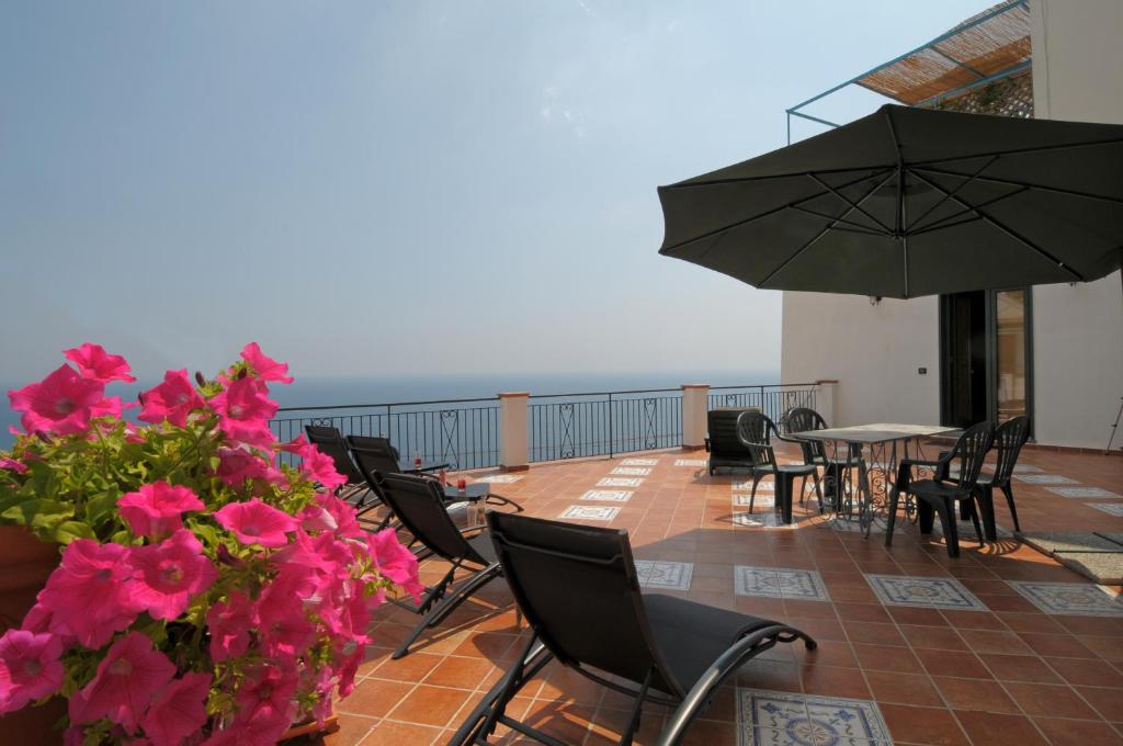 a balcony with a table and chairs and an umbrella at Terrazza di Rosa - sea view in Praiano