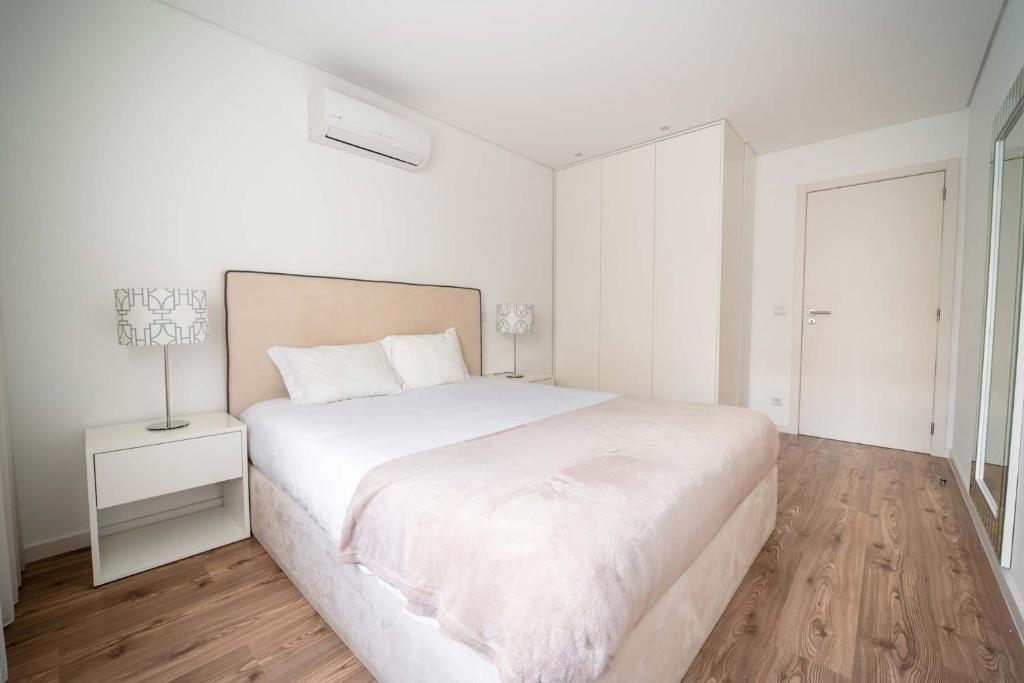 Dormitorio blanco con cama grande y lámpara en Bracara Guest House "São Bento" - "Palácio do Raio", en Braga