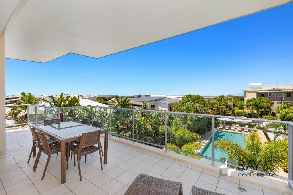 a balcony with a table and chairs and a swimming pool at Luxury Apartments at Bells Blvd in Kingscliff