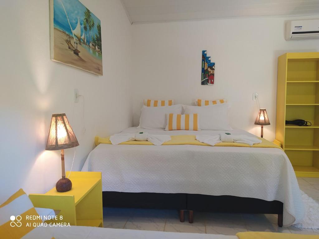 um quarto com uma grande cama branca e um armário amarelo em Pousada João Maria em Trancoso