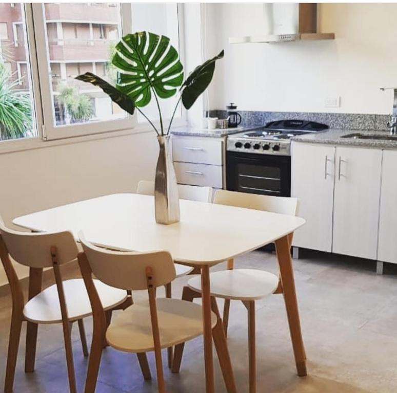 a white kitchen with a table and a plant in a vase at Aliaga Mar del Plata in Mar del Plata