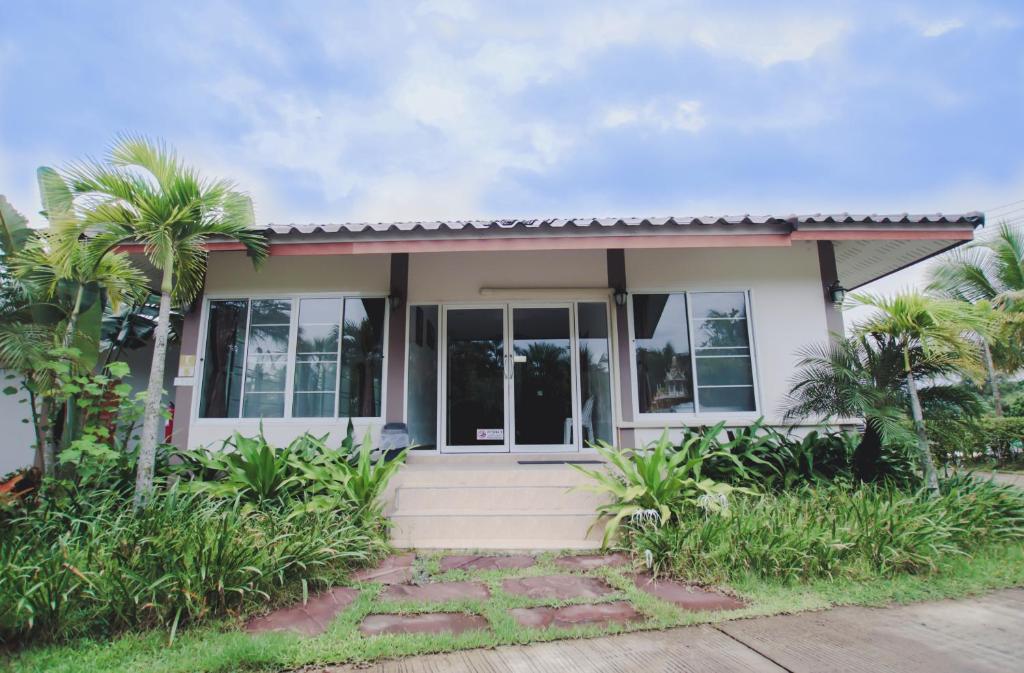 a small house with a porch and palm trees at Lamphurai Riverside Resort and Spa in Trat