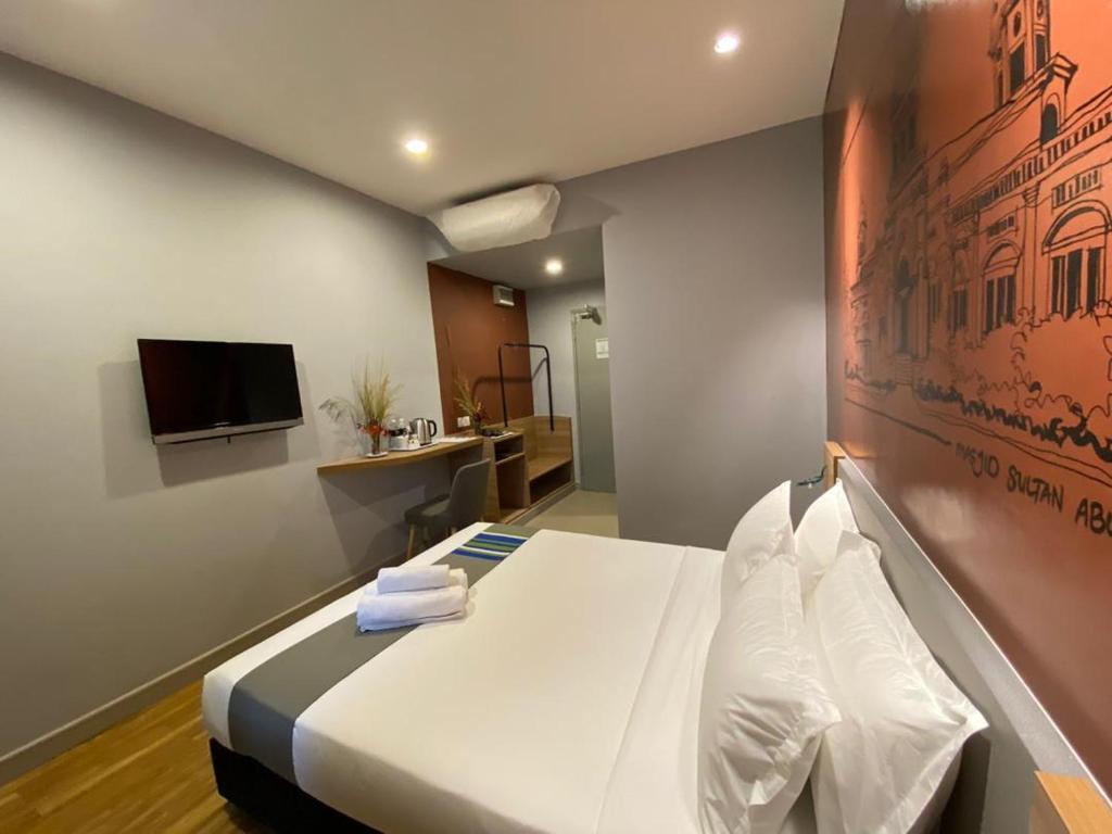 a bedroom with a large bed with a tv on the wall at Singgah Pengerang Hotel in Pengerang
