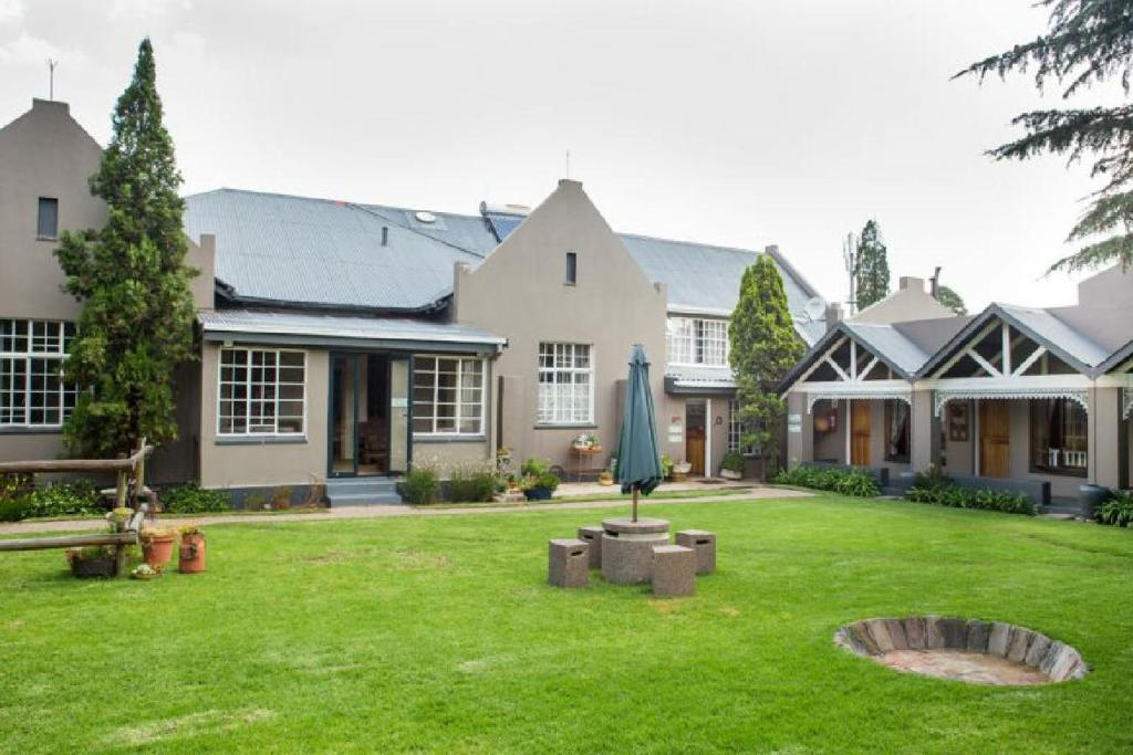 a large house with a green yard with a umbrella at Bo Kamer Guesthouse in Ermelo