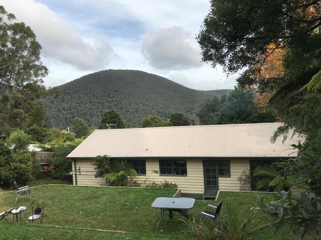 a white house with a mountain in the background at Warburton Holiday House in Warburton