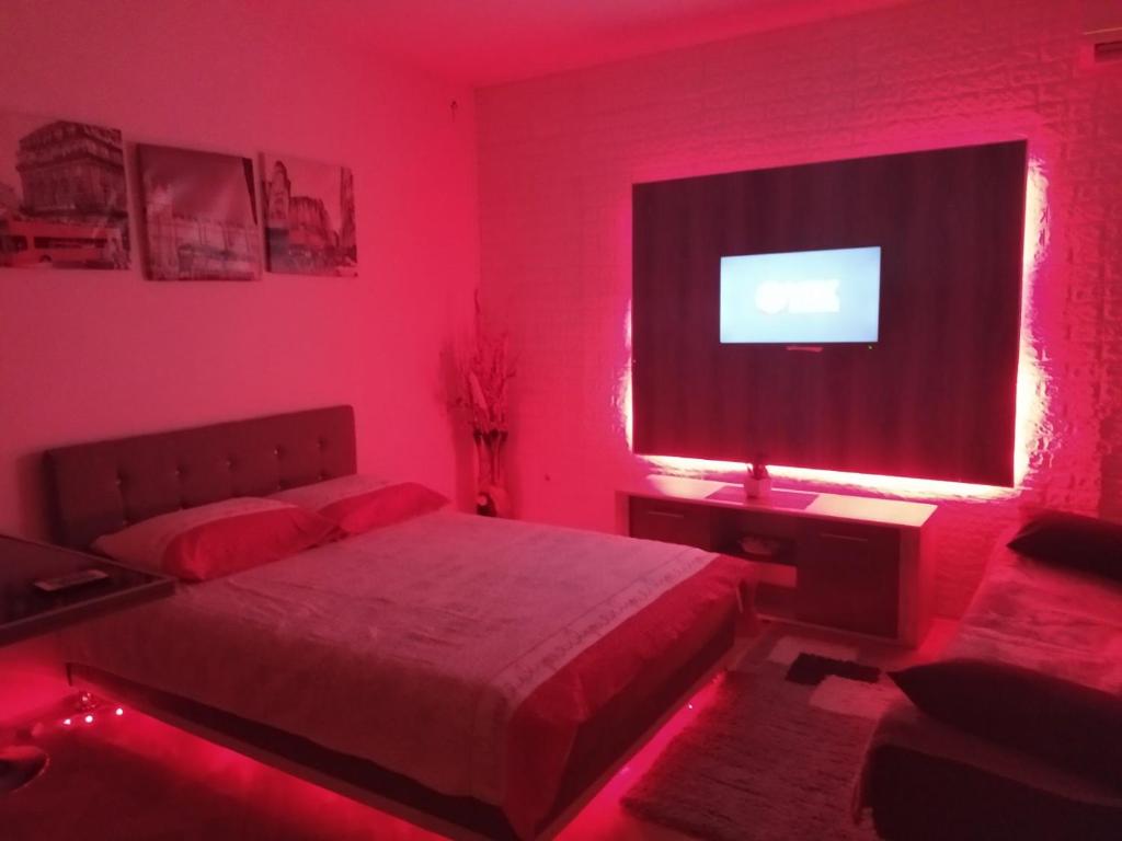 Dormitorio rojo con cama y TV en Apartman Bolero, en Bijeljina