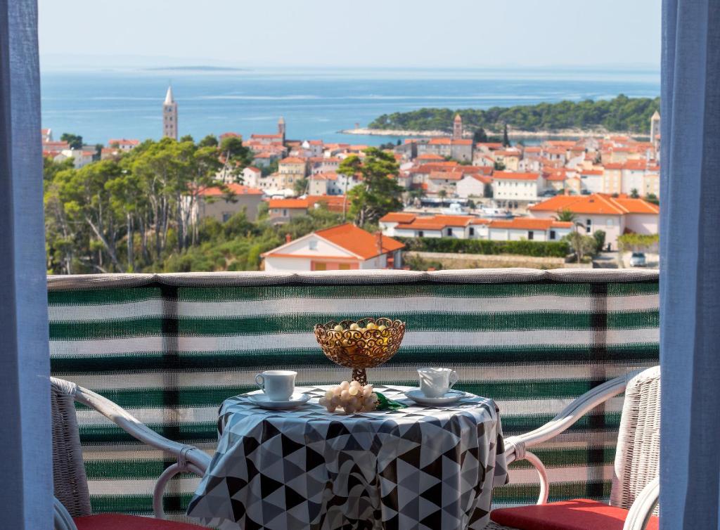 a table on a balcony with a view of a city at Apartment Eneja in Rab