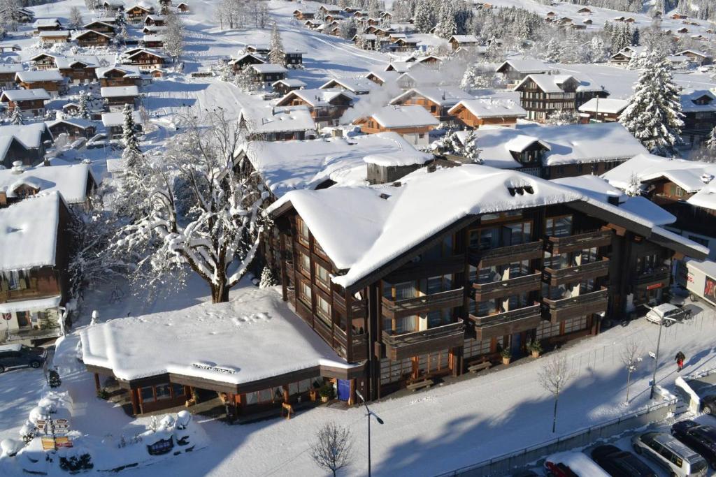miasto pokryte śniegiem z budynkiem w obiekcie Hotel Kreuz Lenk w mieście Lenk