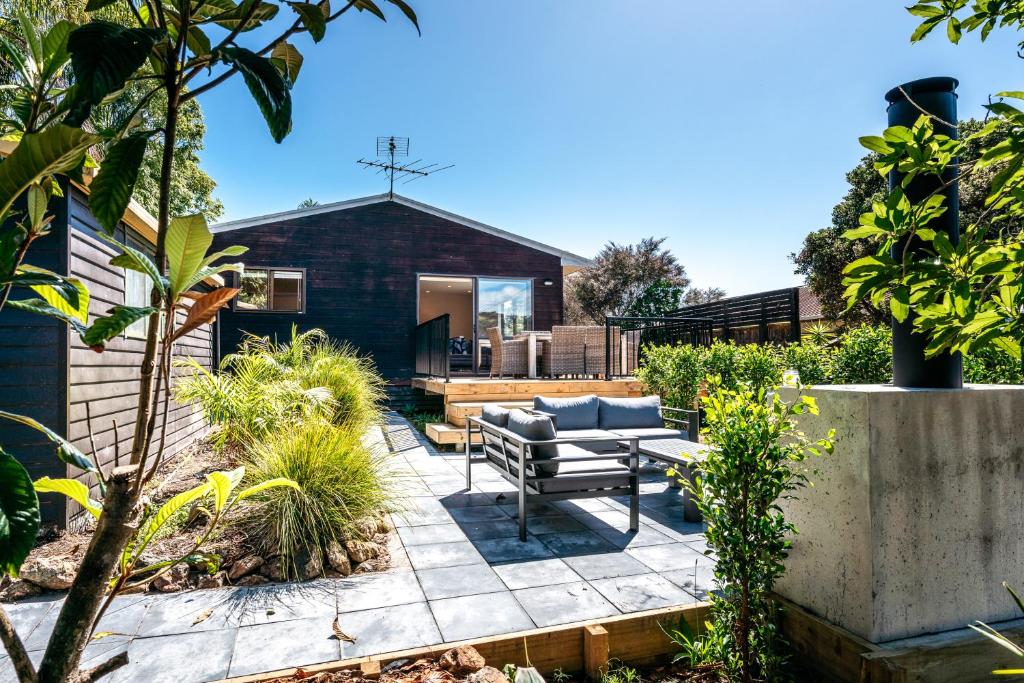 a patio with a couch and a table in a garden at Relax on Ridge in Oneroa