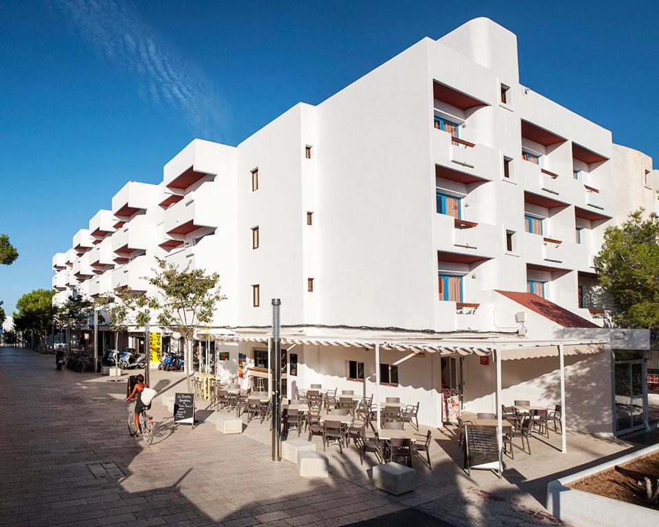 a white building with tables and chairs in front of it at Apartamentos Top Secret Es Pujols - Formentera Vacaciones in Es Pujols
