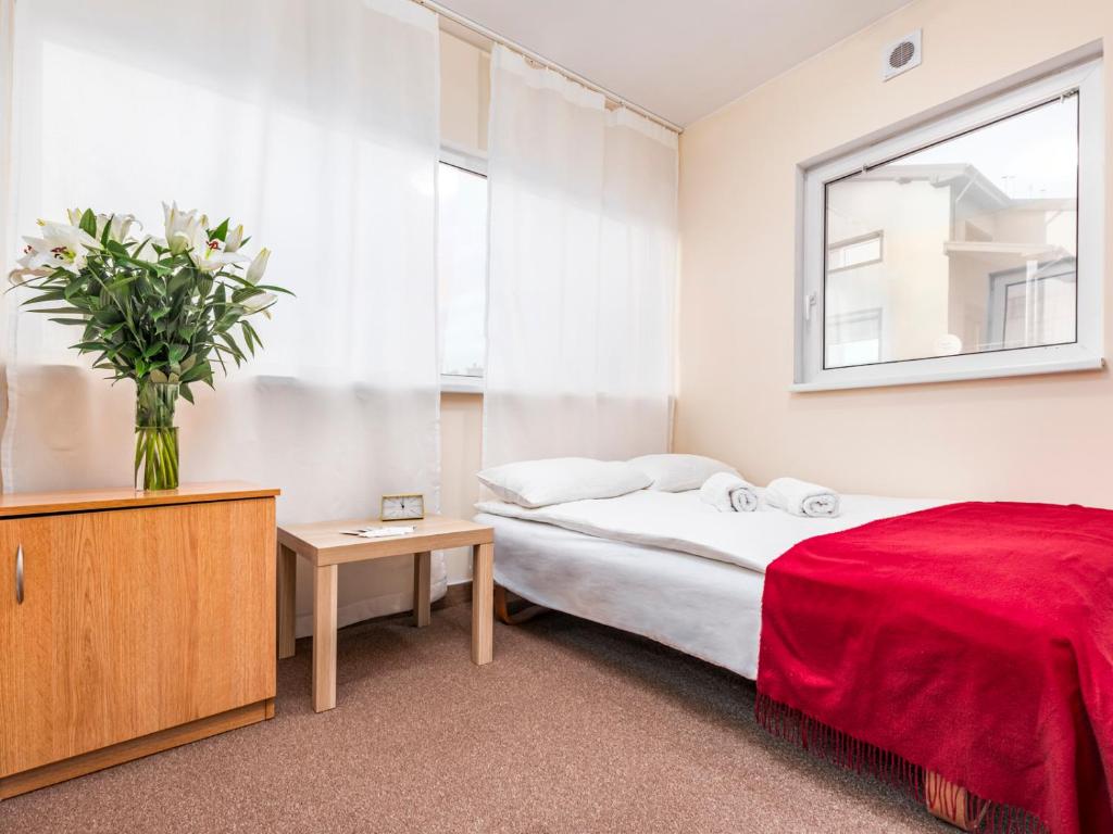 a bedroom with a bed and a vase of flowers at Luxhostel24 Warsaw in Warsaw