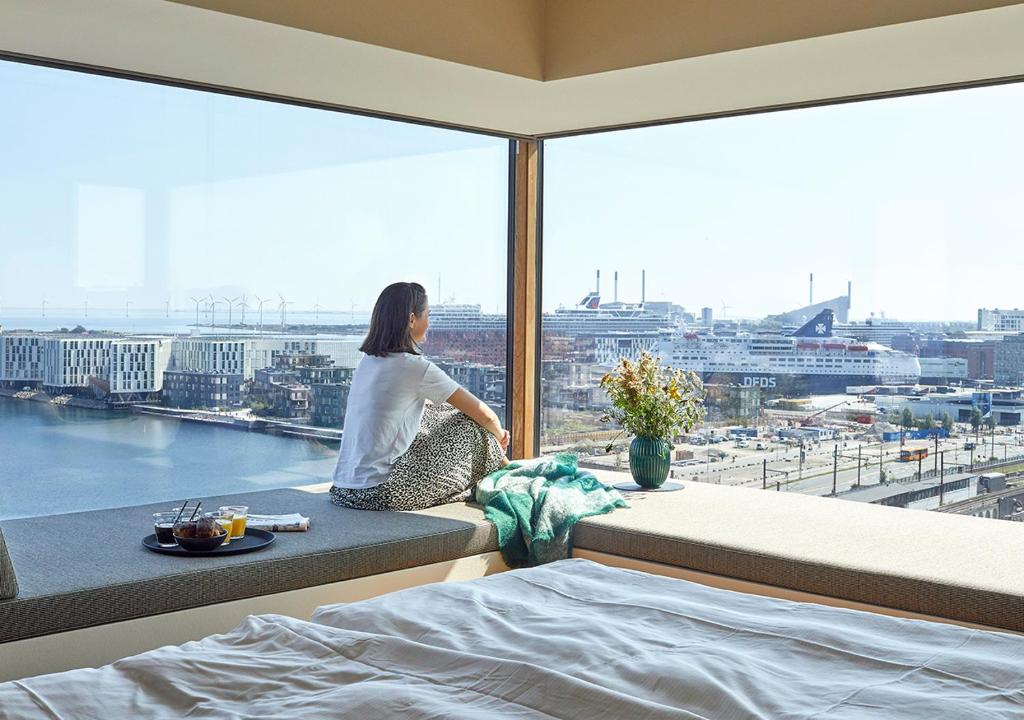 a woman sitting on a window seat looking out at the city at Charlottehaven in Copenhagen