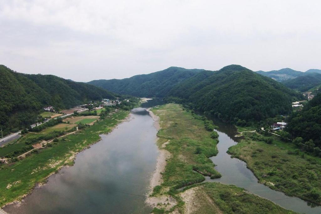 an aerial view of a river with mountains in the background at Forest of Color Pension in Hongcheon
