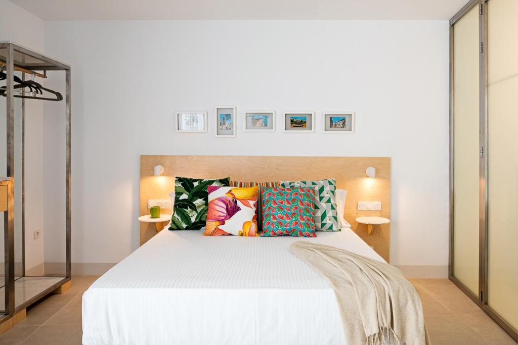 um quarto com uma cama branca e almofadas coloridas em Apartamentos y estudios céntricos Conil Home Suite em Conil de la Frontera