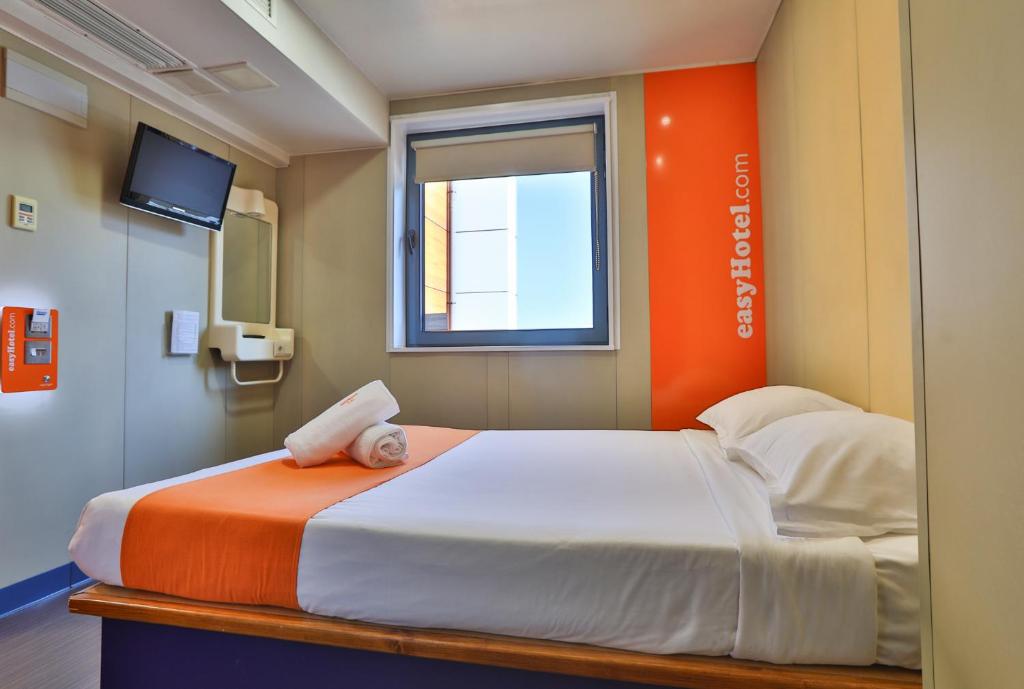 a bedroom with an orange and white bed with a window at easyHotel Sofia in Sofia