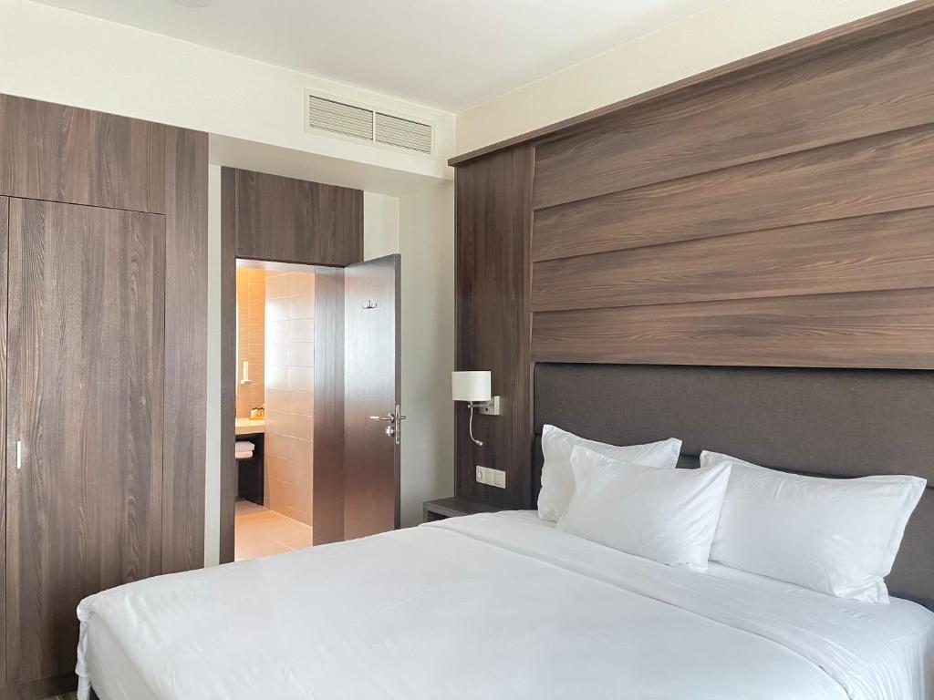 a bedroom with a large white bed with a wooden headboard at Airport Apartment & Office in Sofia