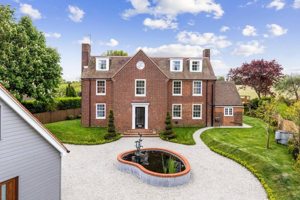 a large brick house with a fountain in the front yard at Stunning 5 Bedroom House - The Officers House in Hawkinge