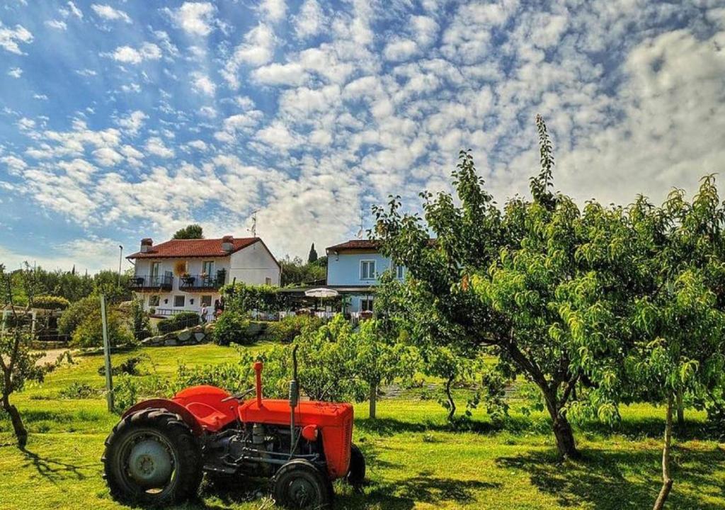 un tractor rojo sentado en un campo frente a una casa en Agriturismo 30, en Moniga del Garda