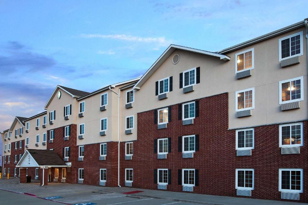 a large brick building with windows on a street at WoodSpring Suites McKinney in McKinney
