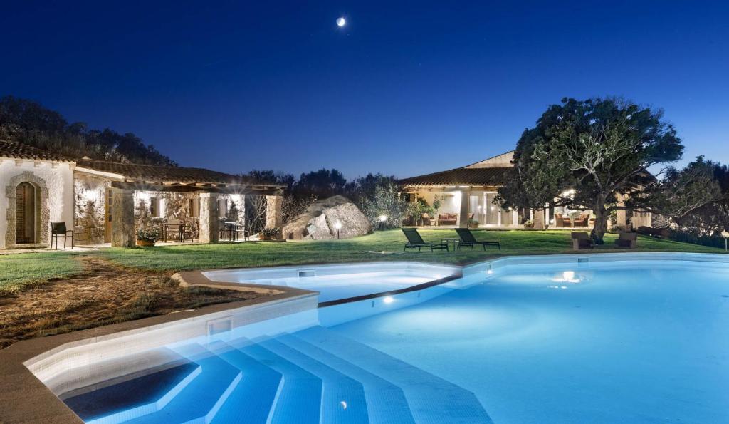 a swimming pool in front of a house at night at Tenuta Pilastru Country Resort & Spa in Arzachena