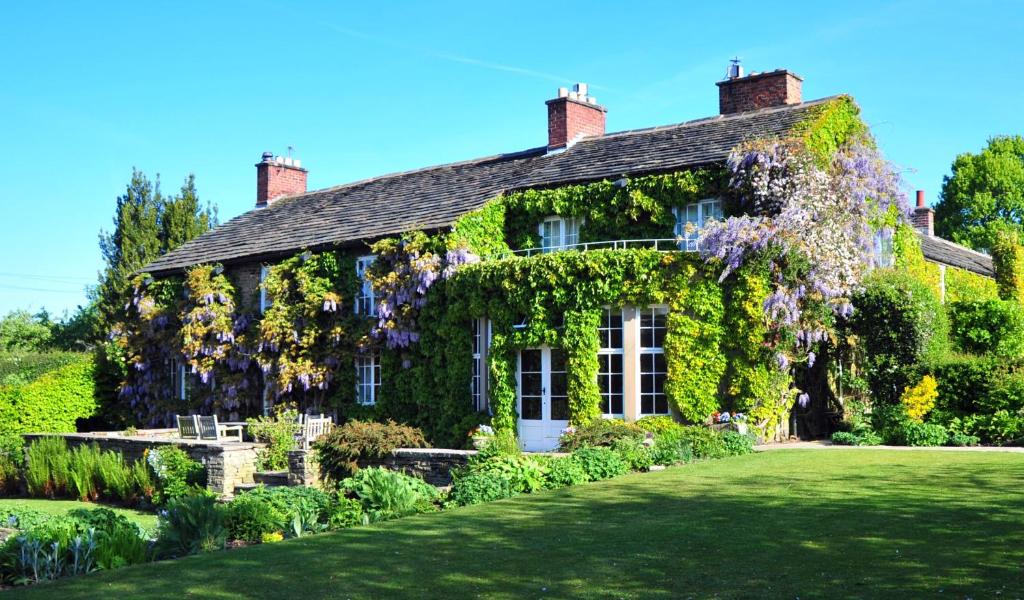 una casa cubierta de hiedra con un jardín delante de ella en Hilltop Country House, en Macclesfield