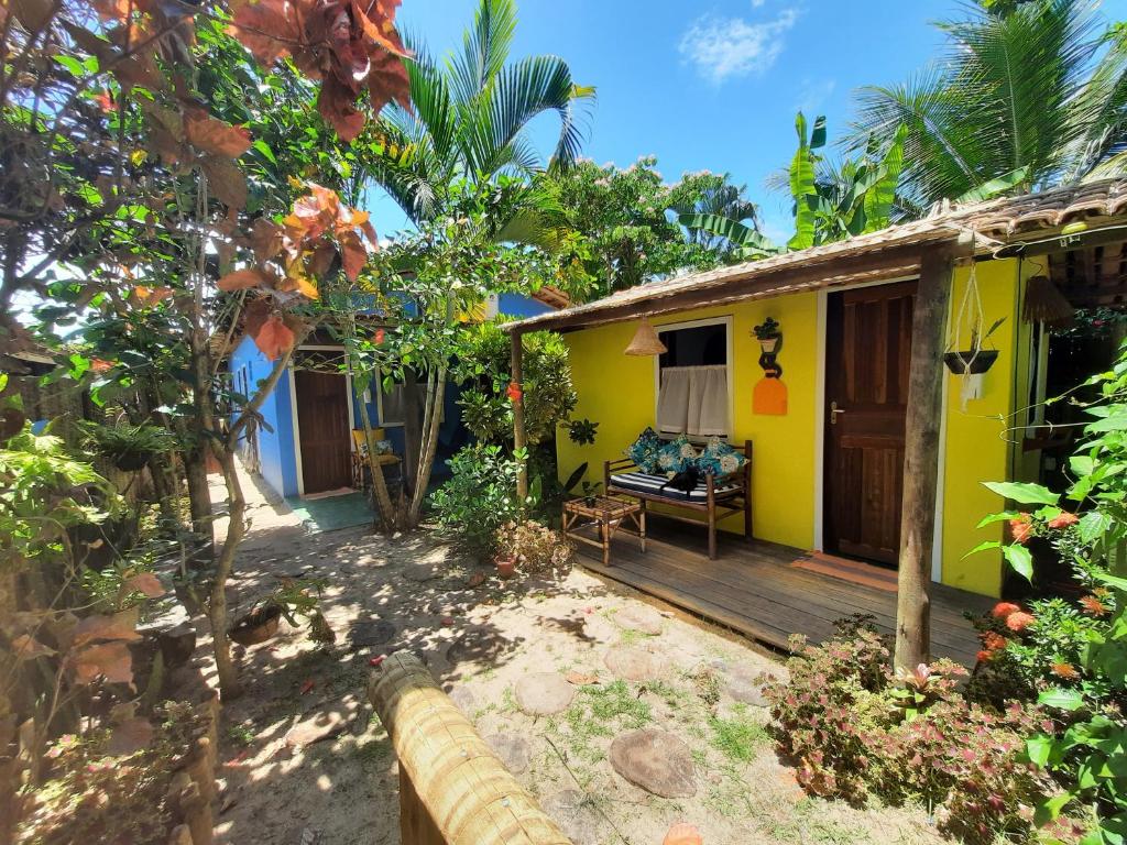 a yellow and blue house with a wooden porch at Hospedaria Caraíva in Caraíva