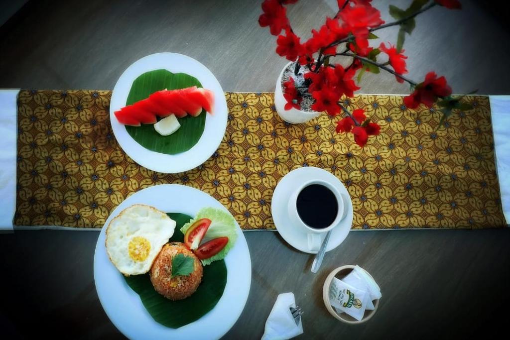 a table with two plates of food and a cup of coffee at Alia Home in Sanur