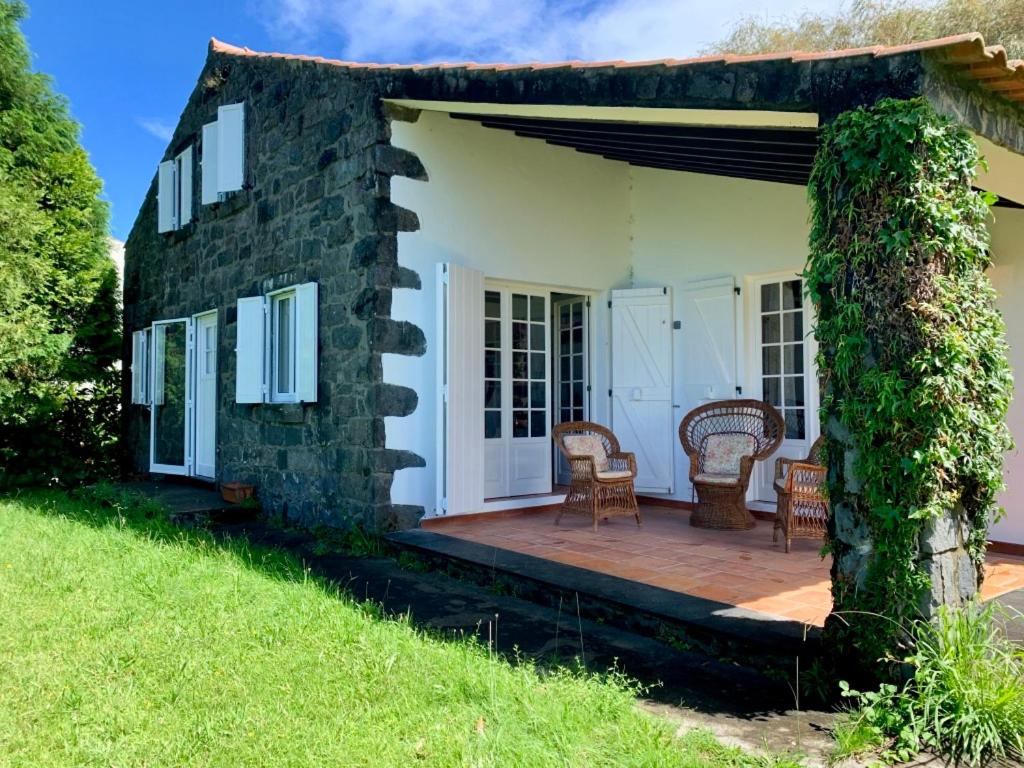 a stone house with a porch and chairs on a deck at Stone House - Sete Cidades in Sete Cidades