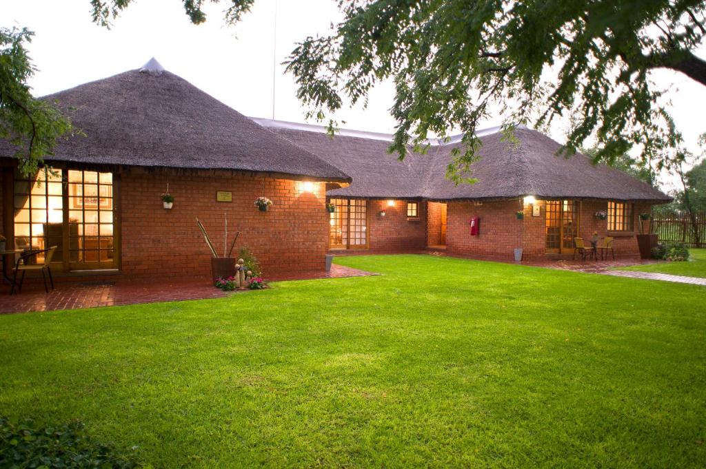 a large brick house with a grass yard at The Willows Guesthouse in Bloemfontein