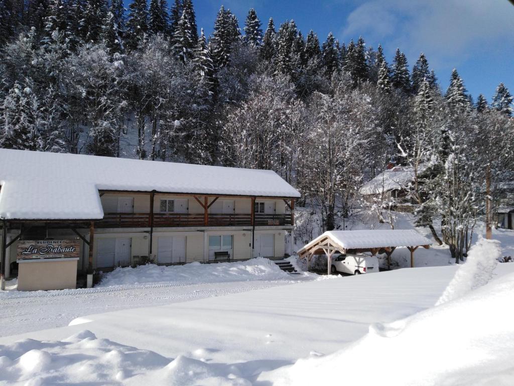 uma casa coberta de neve com árvores ao fundo em Gite de vacances Residence La Babaute LES ROUSSES em Les Rousses