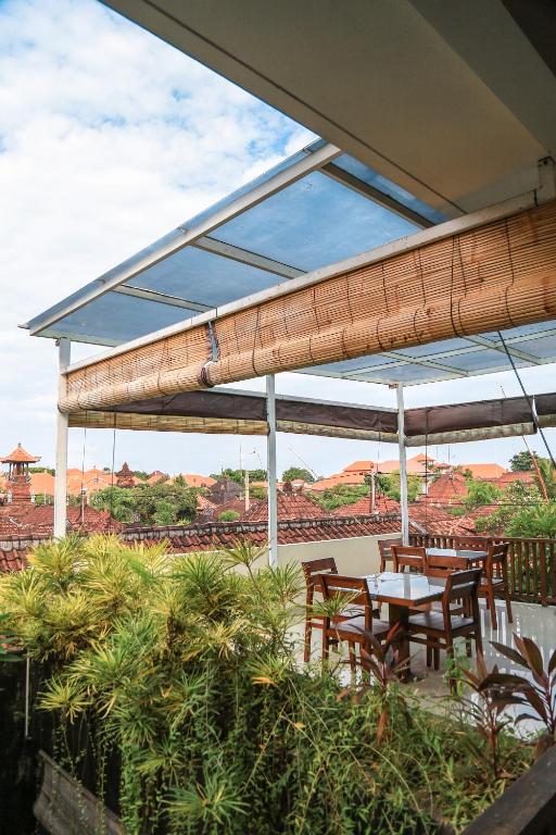 a patio with tables and chairs under awning at Alia Home in Sanur