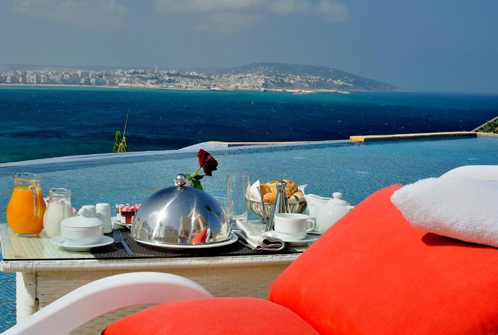 a table with a tea set on it with a view of the ocean at Hotel Farah Tanger in Tangier