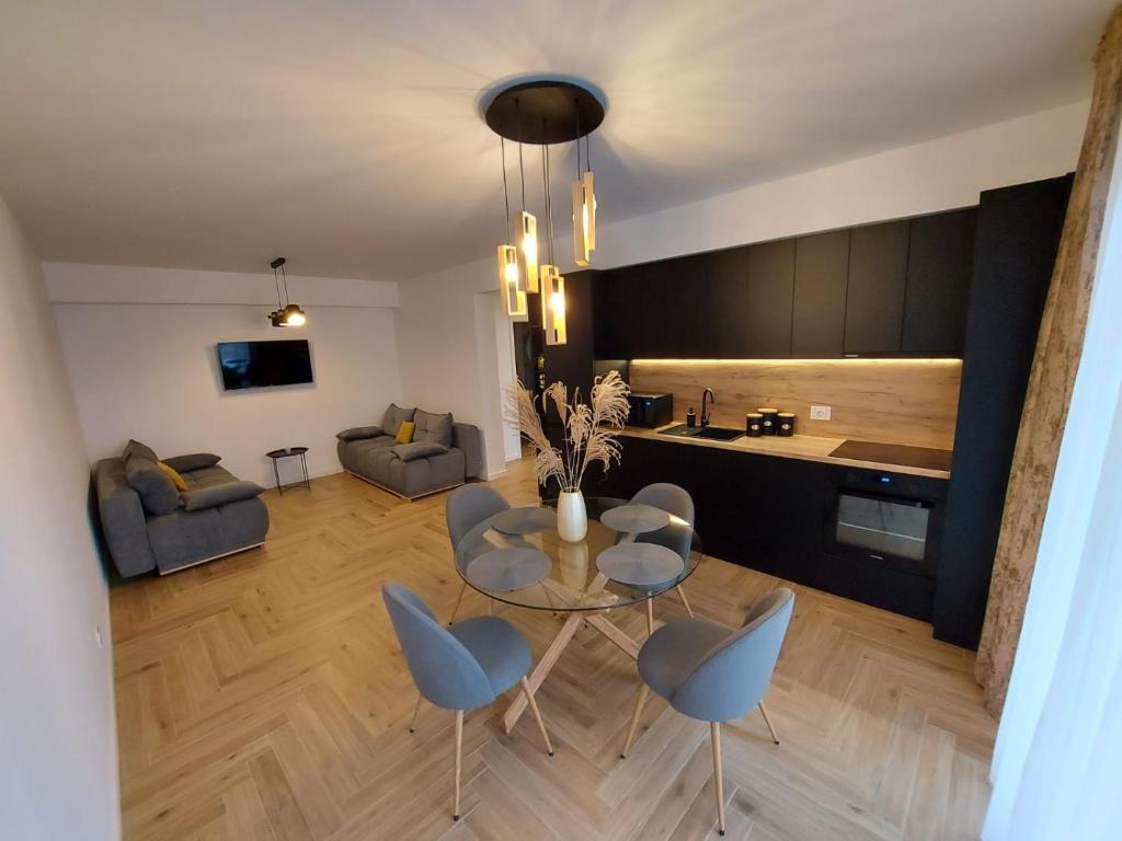 Panoramic Apartments Oradea في أوراديا: غرفة معيشة مع طاولة وكراسي ومطبخ