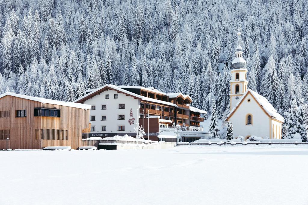 a church and a building in the snow with trees at Hotel Kirchenwirt in Kaunertal