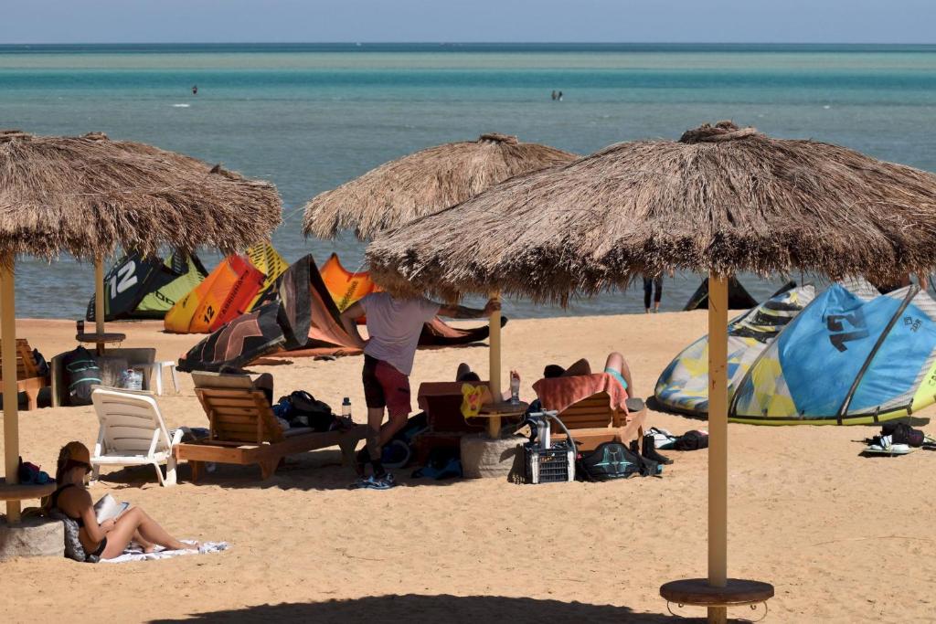 un groupe de personnes sur une plage avec parasols dans l'établissement Royal Beach Serviced Apartments, à Hurghada