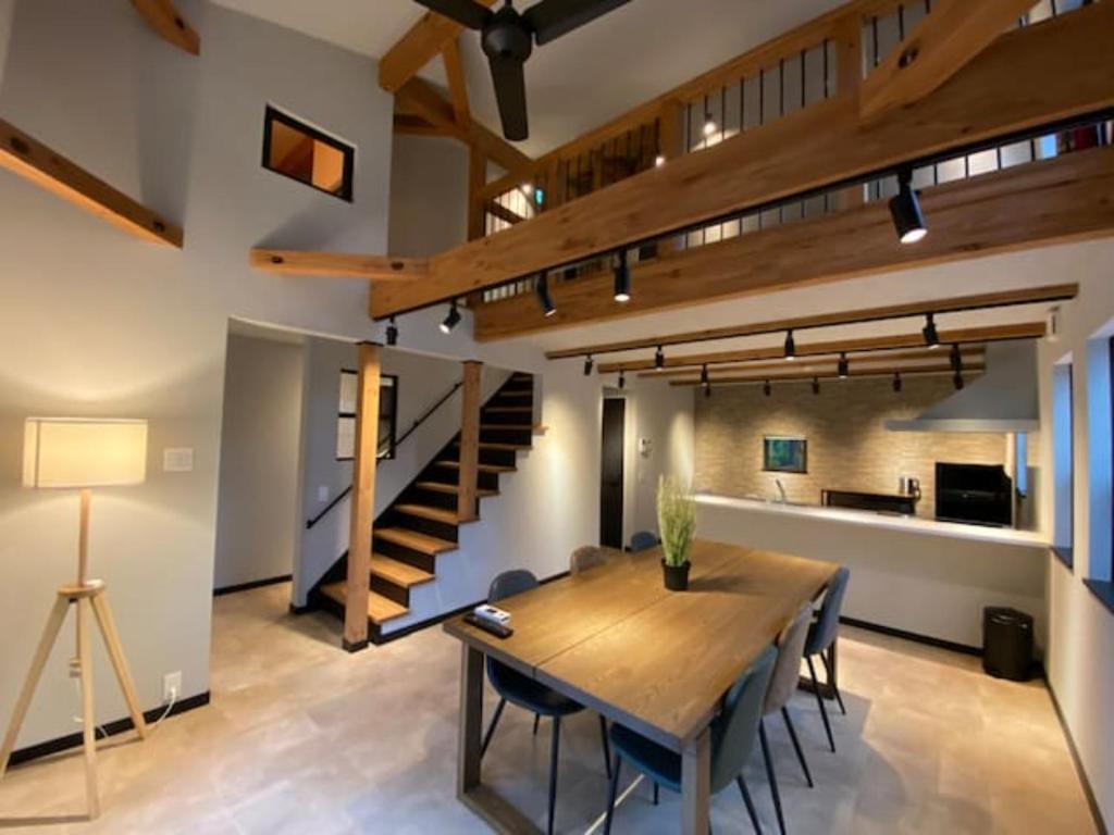 a dining room with a table and a staircase at Stella House ステラハウス in Fujikawaguchiko