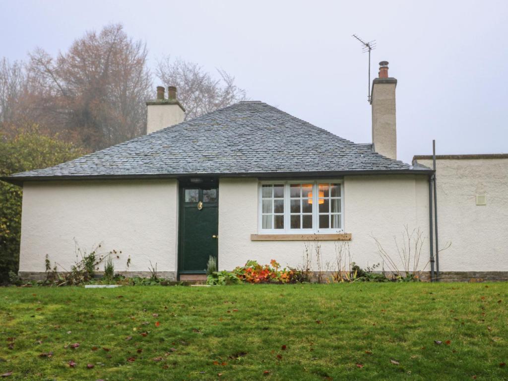 a white house with a green door in a yard at East Cottage - Tarvit in Cupar