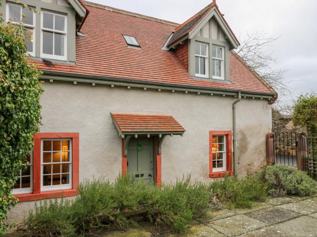 Casa blanca con ventanas rojas y techo en Harmony Cottage - Harmony Gardens en Melrose