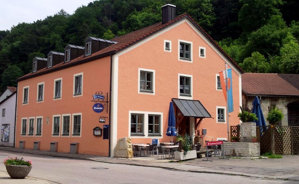 een groot oranje gebouw met tafels en stoelen ervoor bij Gasthof zum Brunnen in Mörnsheim