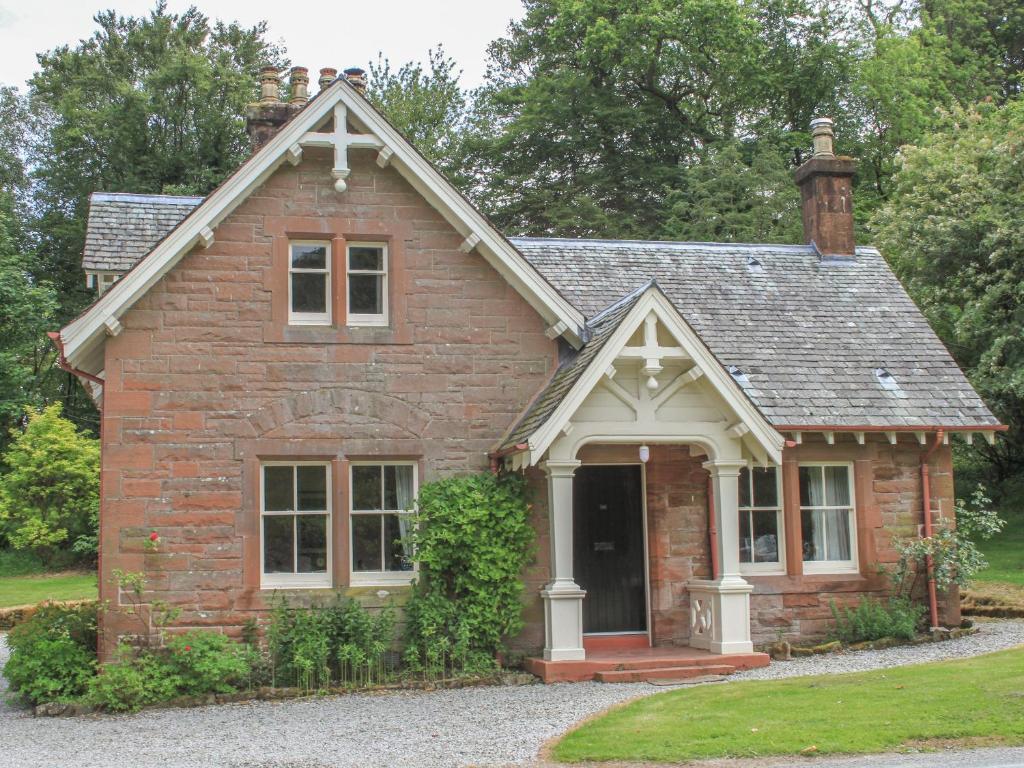 a small red brick house with a large window at Gate Lodge - Threave Estate in Castle Douglas