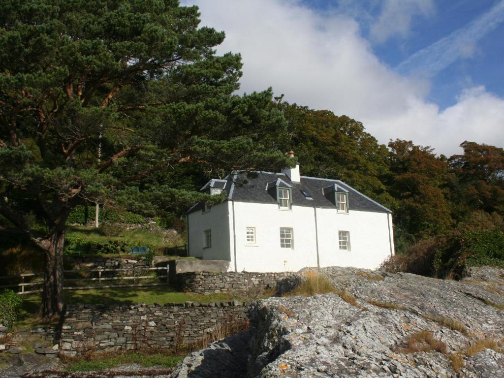 a white house on the side of a hill at Craggan Cottage - Balmacara in Coillemore