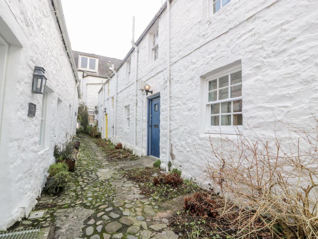 an alley between two white buildings with a blue door at Blue Door - Kirkcudbright in Kirkcudbright