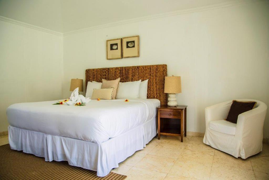 a bedroom with a large white bed and a chair at Bequia Plantation Hotel in Bequia