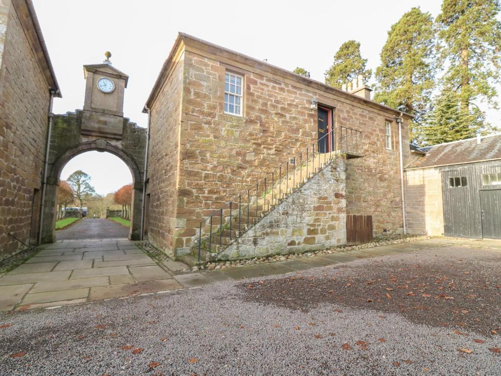 an old brick building with an arch with a clock tower at North Stables - House Of Dun in Montrose