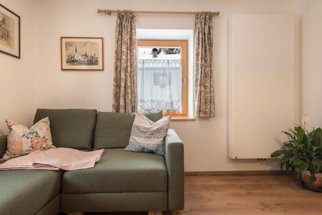ein Wohnzimmer mit einem grünen Sofa und einem Fenster in der Unterkunft Apartment Santer Villa Erna in Seis am Schlern
