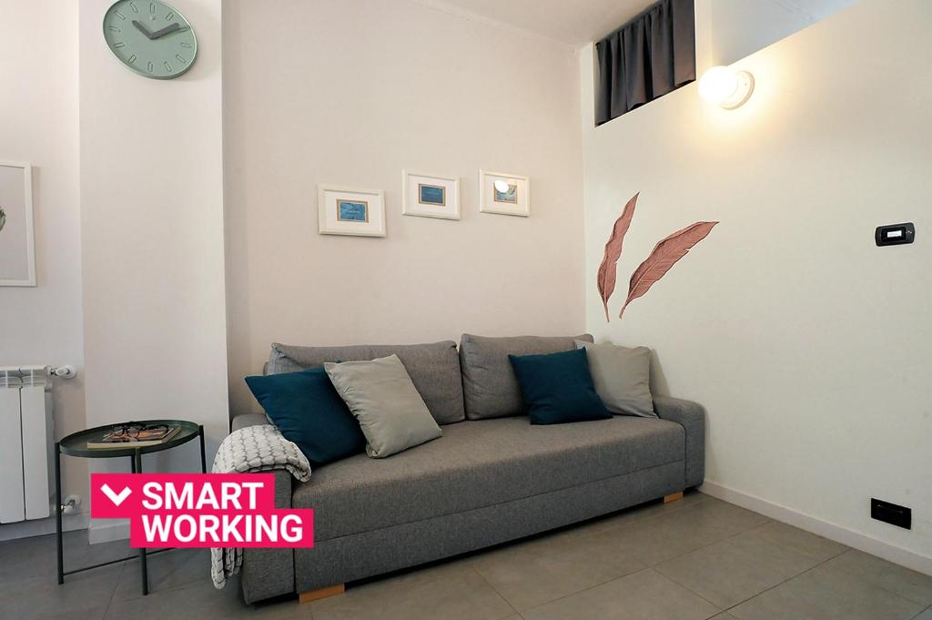 a couch in a living room with a clock on the wall at Modern Apartment in Lingotto Area by Wonderful Italy in Turin