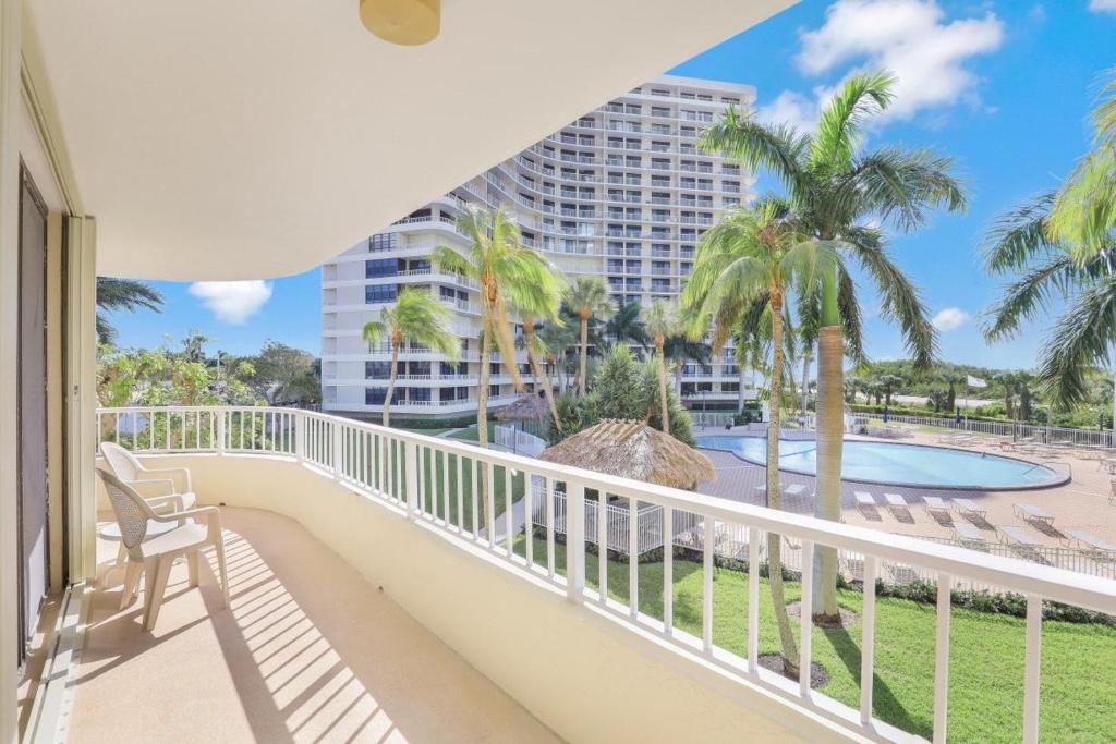 a balcony with a view of a pool and palm trees at Ideal beachfront condo with pool and two balconies in Marco Island