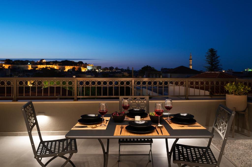 a table with chairs and wine glasses on a balcony at Petalo Suites in Rethymno Town