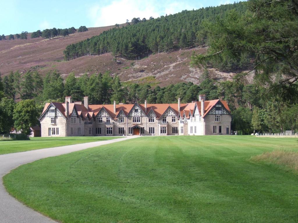 une grande maison avec une pelouse verte en face d'une montagne dans l'établissement Braeriach - Mar Lodge Estate, à Ballater