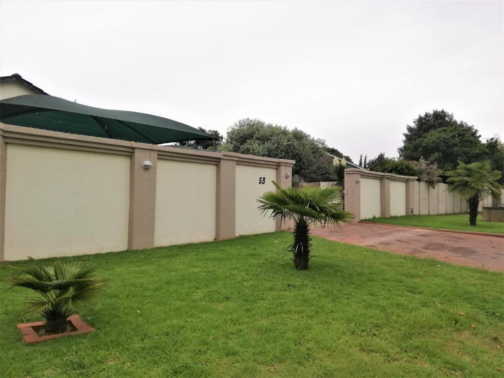 a row of buildings with palm trees in the grass at Franchise Premier Guest House in Boksburg